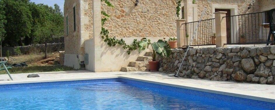 Piscina junto a una vivienda de piedra con zócalo de canto rodado