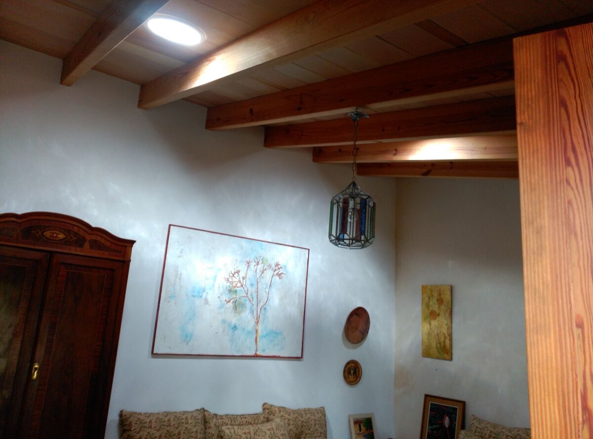 Salón con techo de vigas de madera y luminarias empotradas