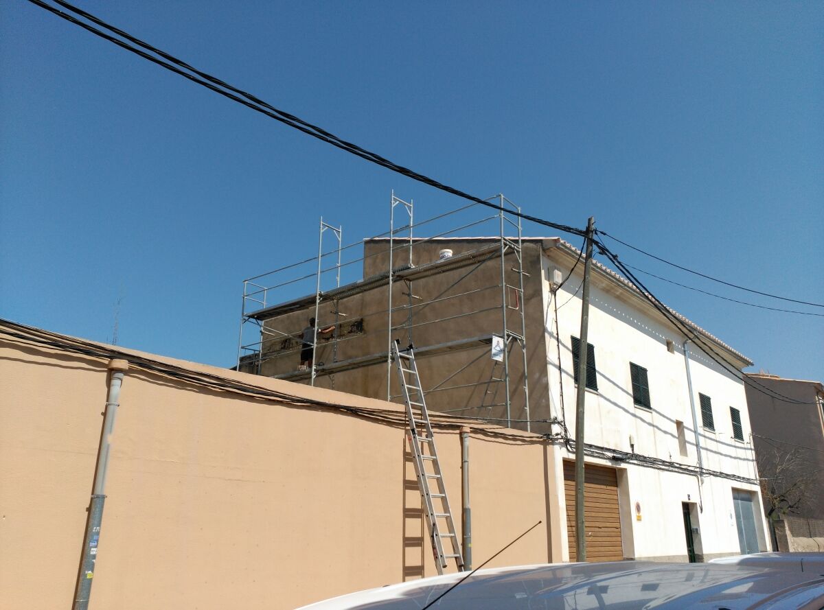 Fachada de edificio entre medianeras con andamio y escalera de obra