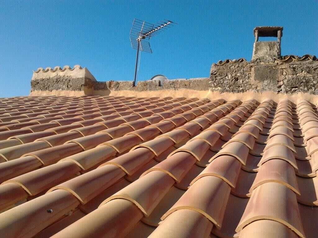Cubierta de teja terminada con antena y remate de piedra