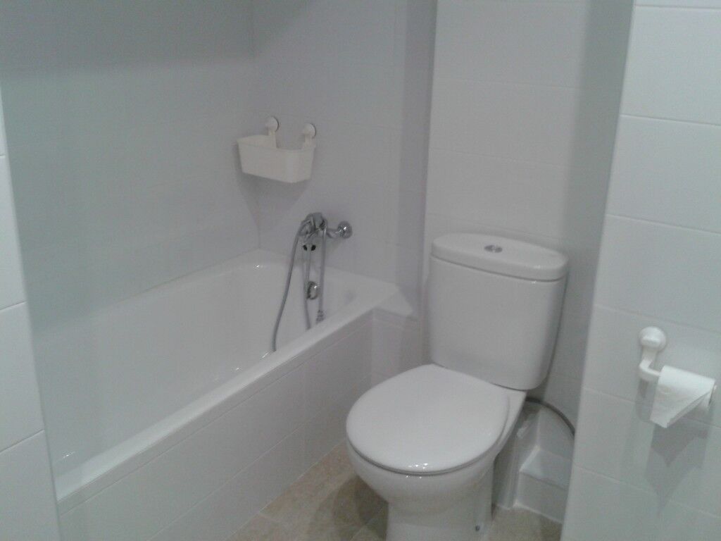 Baño con bañera e inodoro, alicatado en blanco