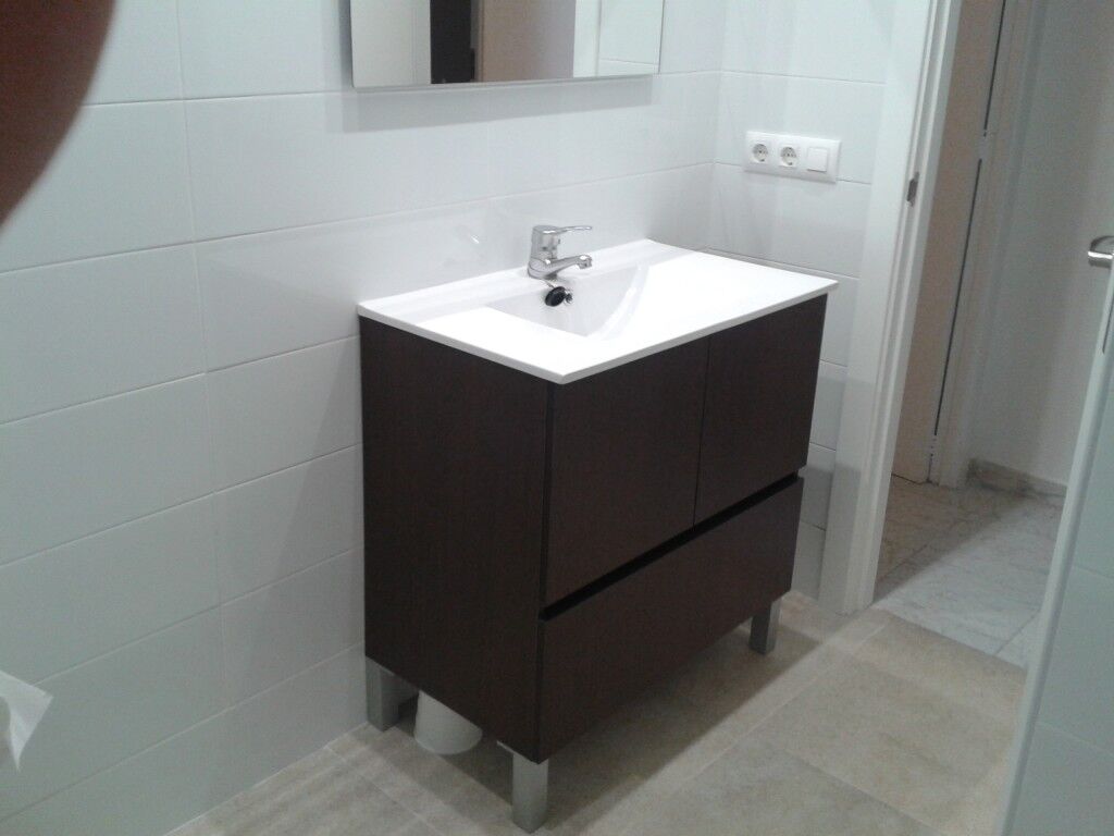 Baño con mueble suspendido de madera oscura y espejo
