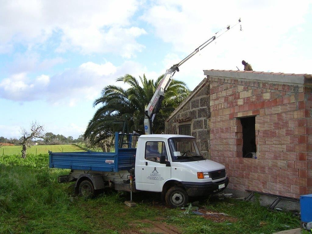 Camión grúa en una edificación de piedra en el campo